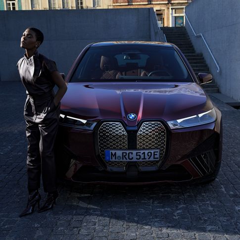Vue avant de la BMW iX avec modèle Vue avant de la BMW iX Aventurinrot i20 avec modèle