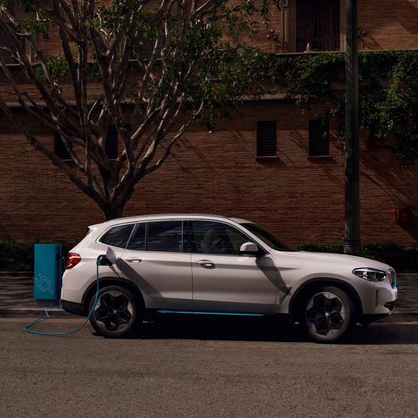 High Power Charging BMW iX3 G08 sur une borne de recharge publique, vue de profil High-Power Charging BMW iX3 G08 2020 Mineralweiß metallic sur une borne de recharge publique, vue de profil