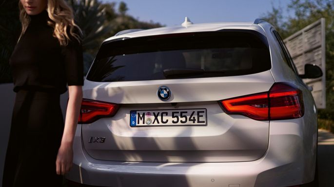 Poupe avec diffuseur BMW i spécifique de la BMW iX3 G08, vue arrière avec femme Poupe avec diffuseur spécifique BMW i de la BMW iX3 G08 2020 Mineralweiß metallic, vue arrière avec femme