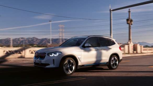 Suspension M adaptative BMW iX3 G08 en mouvement sur la route Suspension M adaptative BMW iX3 G08 2020 en Mineralweiß metallic, vue de trois quarts avant en mouvement sur la route
