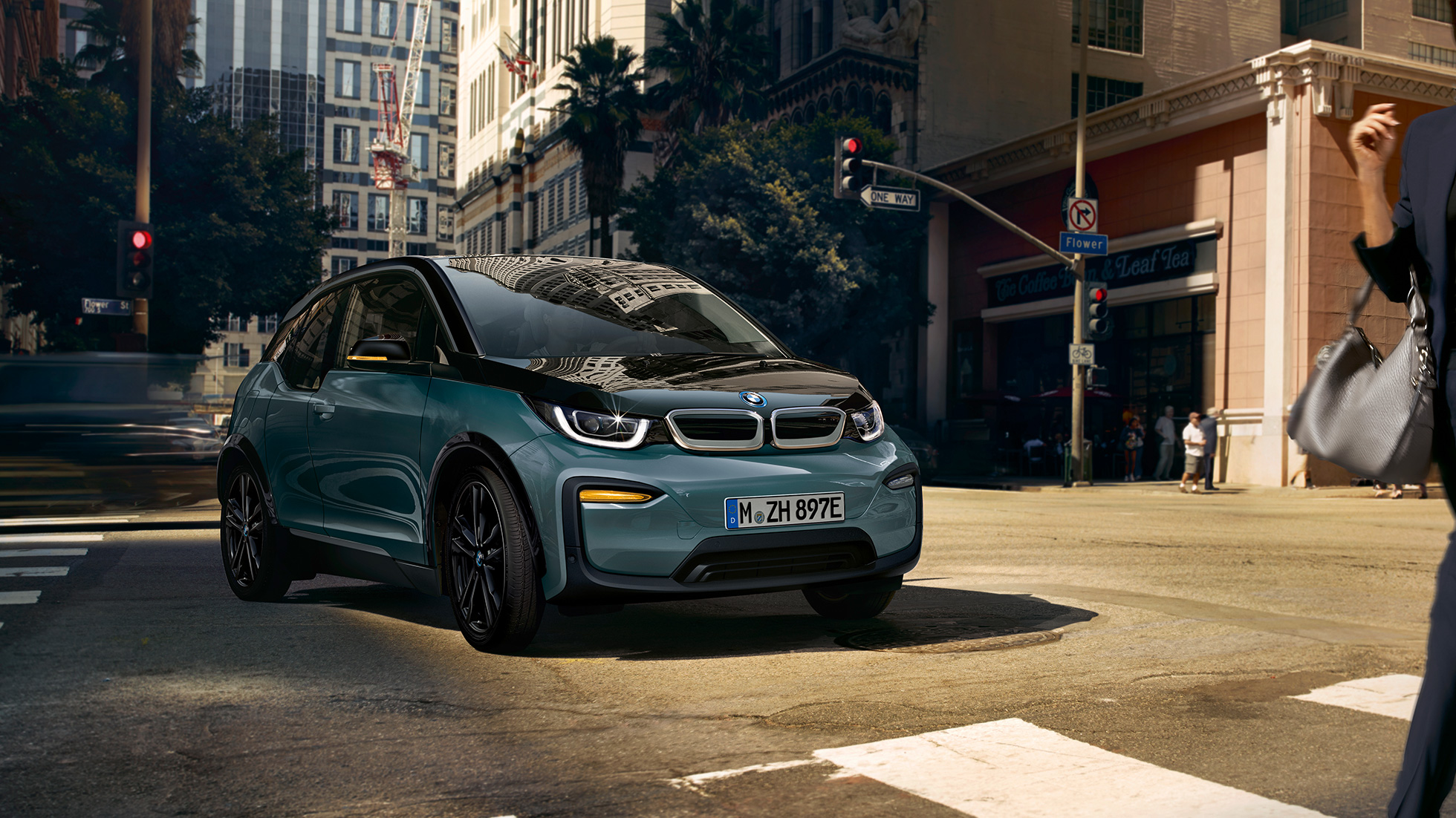 BMW i3 2018, vue de trois quarts avant en mouvement BMW i3 I01 2018 Jucarobeige avec accent Frozen Grey metallic vue de trois quarts avant roulant dans un décor urbain