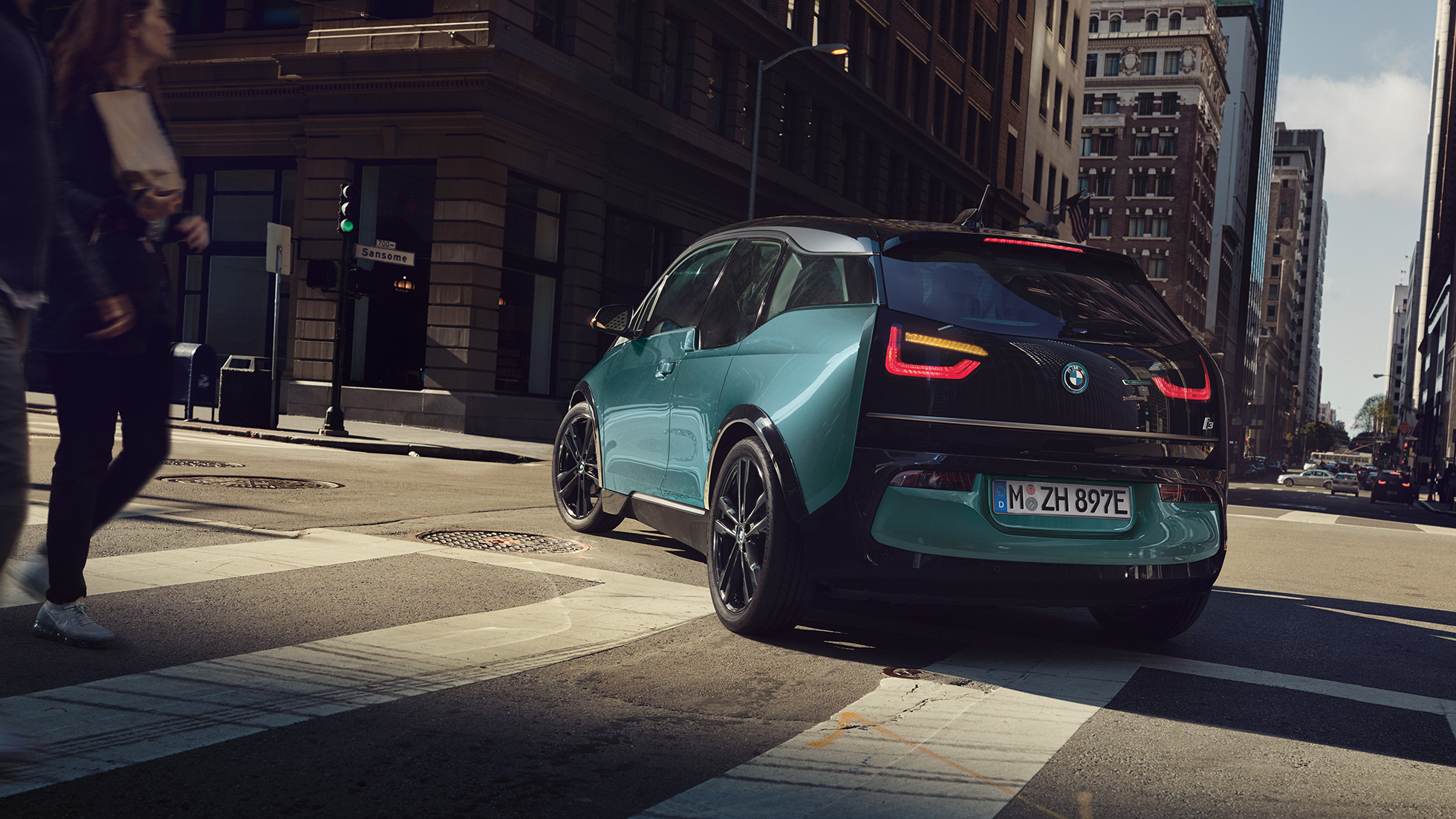 BMW i3 2018 vue de trois quarts arrière, en mouvement BMW i3 I01 2018 Jucarobeige avec accent Frozen Grey metallic vue de trois quarts arrière roulant dans un décor urbain