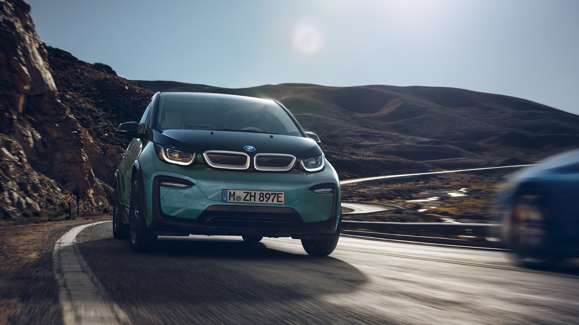 BMW i3 2018 vue de profil en mouvement BMW i3 I01 2018 Jucarobeige avec accent Frozen Grey metallic vue de profil roulant dans un décor urbain
