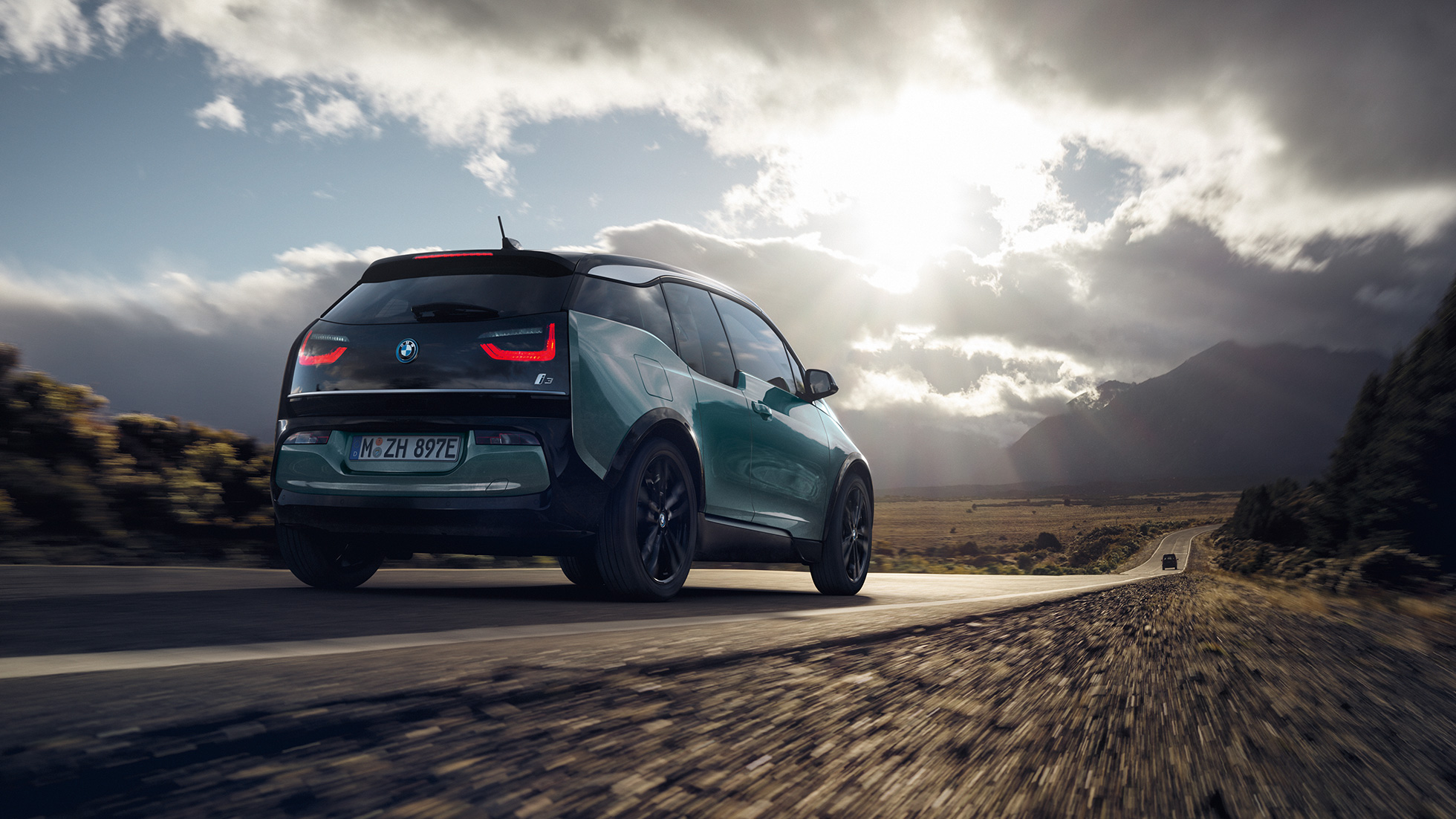 BMW i3 2018 Jucarobeige vue de trois quarts arrière roulant sur une route de campagne BMW i3 I01 2018 Jucarobeige avec accent Frozen Grey metallic vue de trois quarts arrière roulant sur une route de campagne