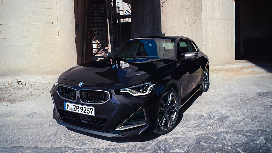 BMW M240i xDrive Coupé G42 2021 vue de trois quarts avant à l’arrêt BMW M240i xDrive Coupé G42 2021 Black Sapphire metallic, vue de trois quarts avant devant entrepôt