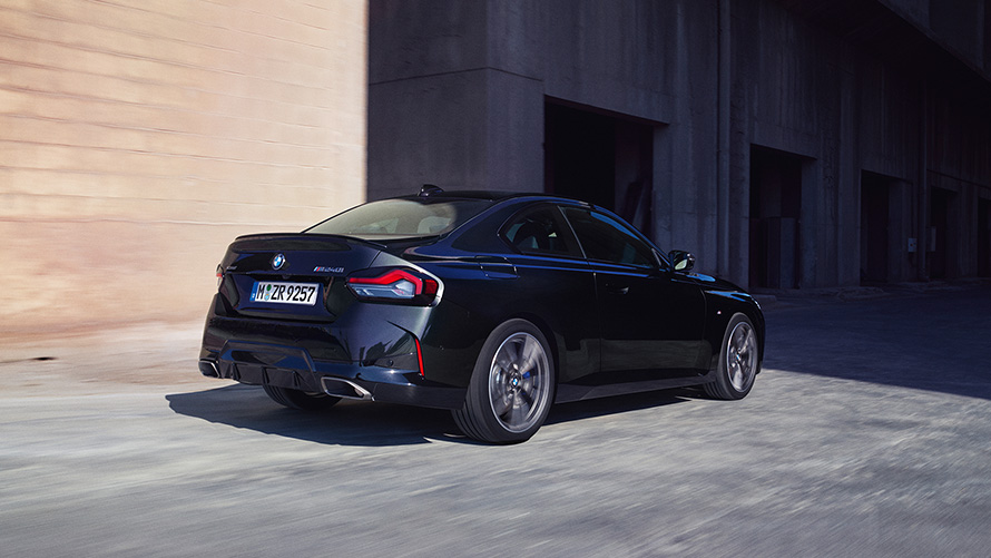 BMW M240i xDrive Coupé G42 2021 vue de trois quarts arrière à l’arrêt BMW M240i xDrive Coupé G42 2021 Black Sapphire metallic vue de trois quarts arrière à l’arrêt devant entrepôt