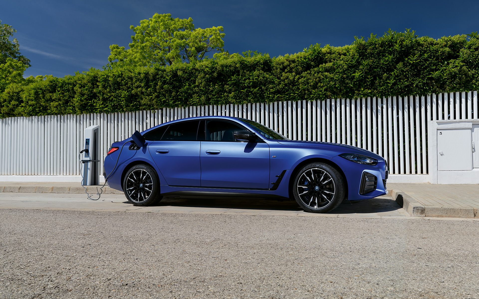 BMW i4 M50 G26 2021 BMW Individual Frozen Portimao Blau metallic branchée à une borne de recharge vue de profil