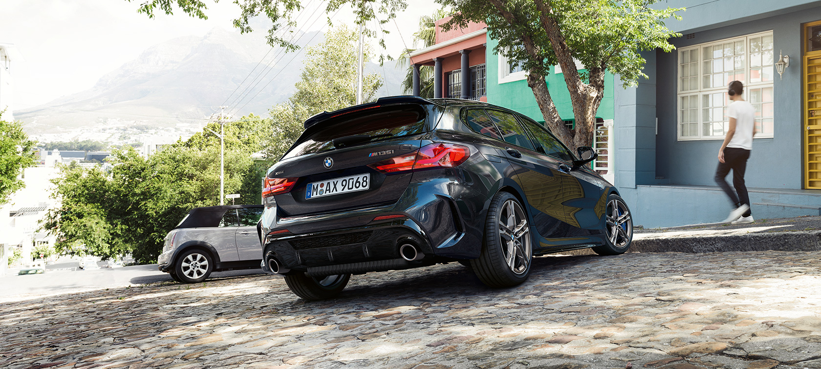 BMW M135i xDrive, vue de trois quarts arrière. BMW M135i xDrive en Saphirschwarz metallic, vue de trois quarts arrière, en stationnement devant une habitation.