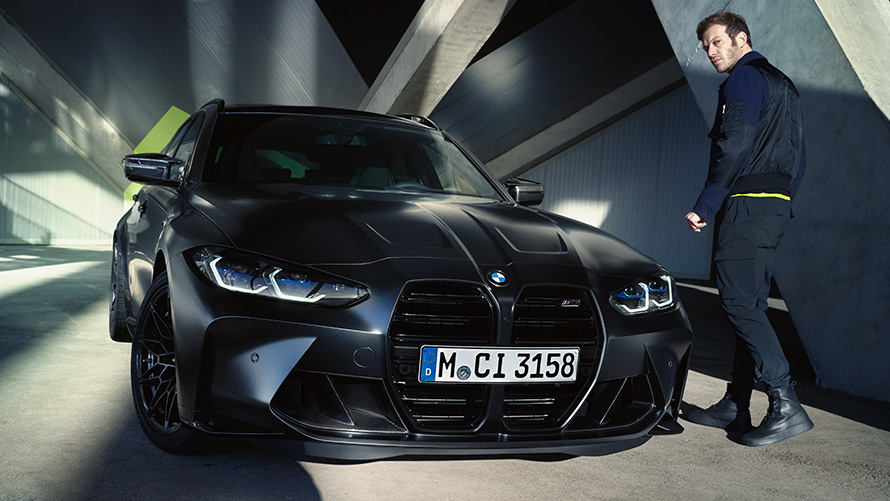 BMW M3 Competition Touring G81 vue de trois quarts avant à l’arrêt avec modèle BMW M3 Competition Touring G81 BMW Individual Frozen Black metallic vue de trois quarts avant à l'arrêt avec modèle