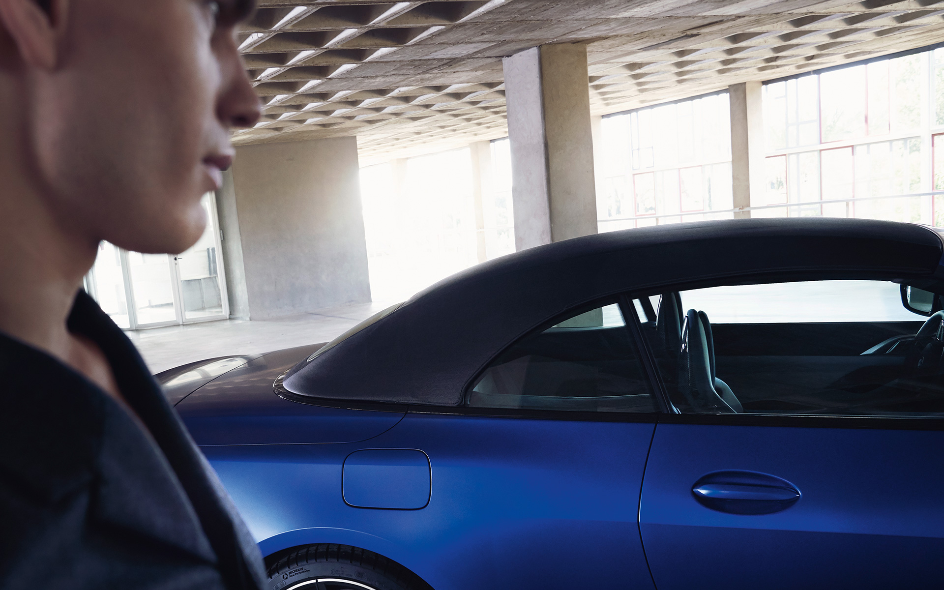 BMW M4 Competition Cabrio avec M xDrive G83 2021 BMW Individual Frozen Portimao Blau metallic avec capote en tissu fermée et homme à l’avant-plan