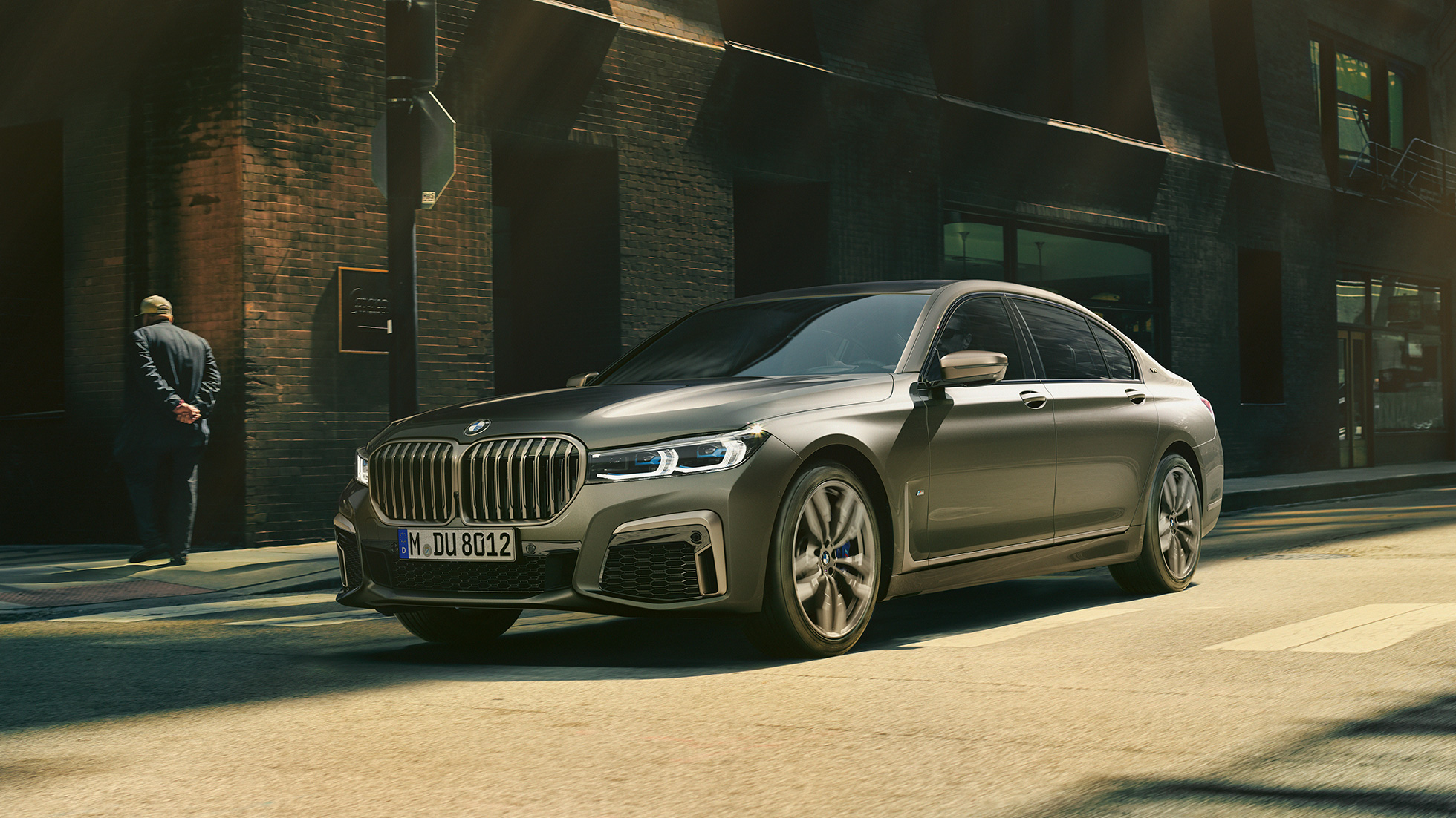 BMW M760Li xDrive Berline dans un décor urbain BMW M760Li xDrive Berline, se déplaçant sur une route dans un décor urbain, vue de profil de la partie avant du véhicule.