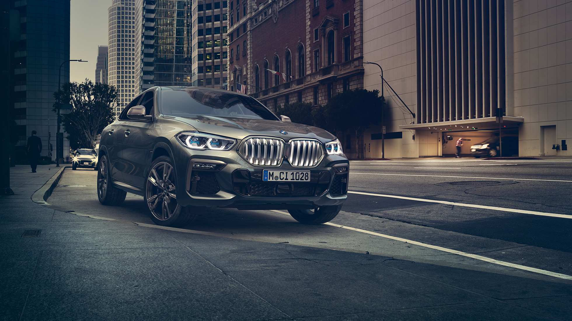 BMW X6 M50i à l’arrêt La BMW X6 M50i vue de trois quarts avant, à l’arrêt devant un décor urbain