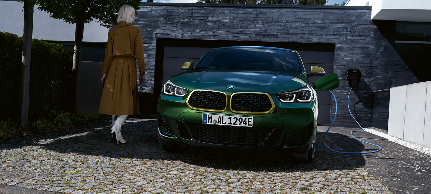 Vue avant de la BMW X2 F39 Sanremo Green metallic Vue avant en recharge avec modèle à gauche BMW X2 F39 Sanremo Green metallic