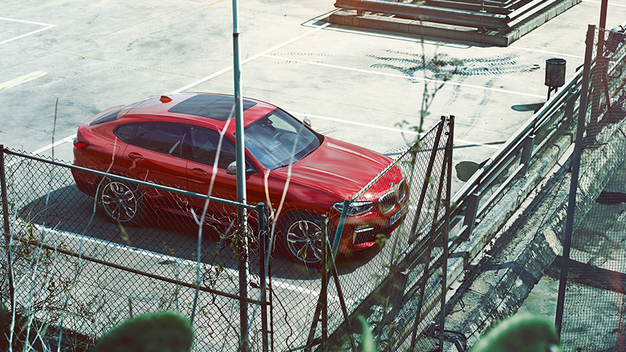 BMW X4 en stationnement BMW X4 G02 2018 en Flamencorot Brillanteffekt en stationnement sur un parking couvert, vue en plongée